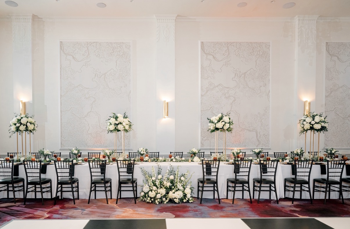 Wedding head table with tall floral arrangements in the historic ballroom at The Gunter Hotel