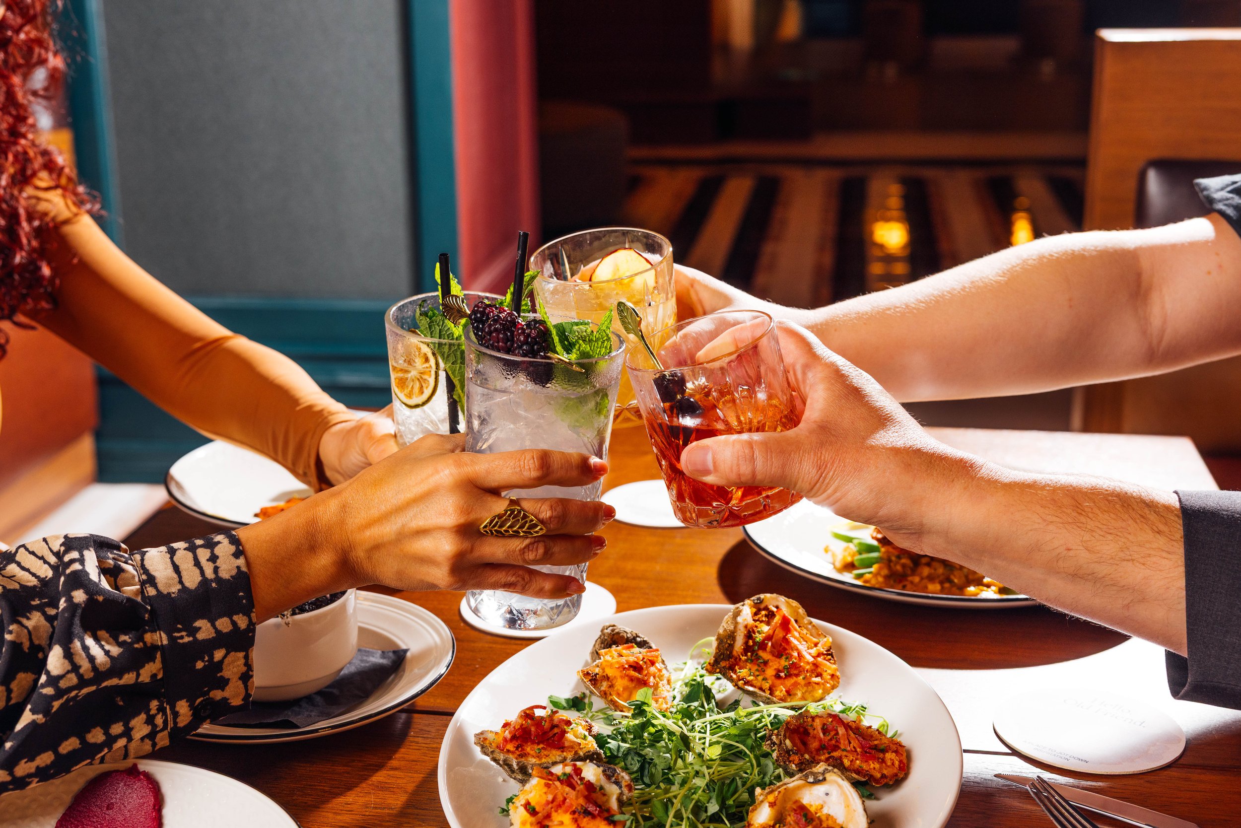 Guests toasting cocktails over shared plates at The Gunter Hotel