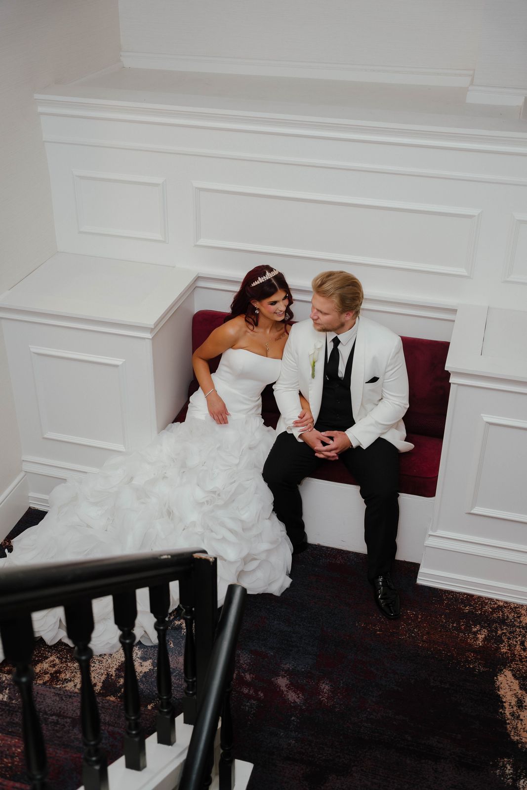 Bride and groom seated together on a red banquette